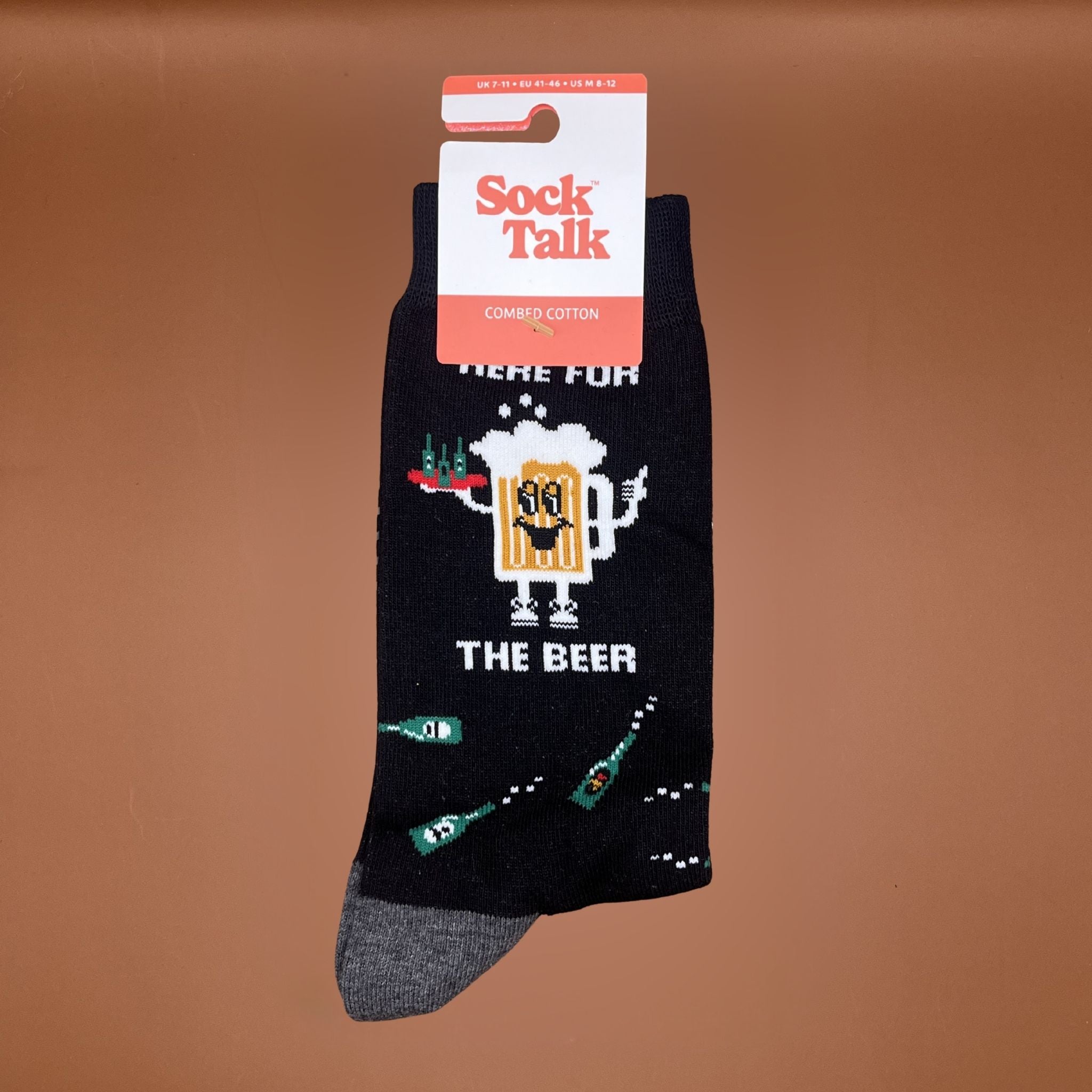 Navy blue socks with beer-themed design, featuring beer bottles and a smiling beer mug with the text “Here for the beer.”