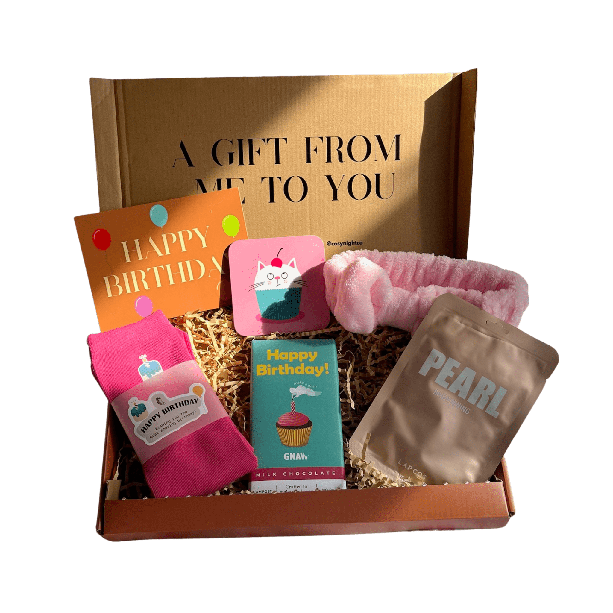 Birthday letterbox gift box from Cosy Night Co featuring pink “Happy Birthday” socks, GNAW milk chocolate bar, pink headband, PEARL face mask, cat coaster, and birthday card, beautifully packed in a gift box