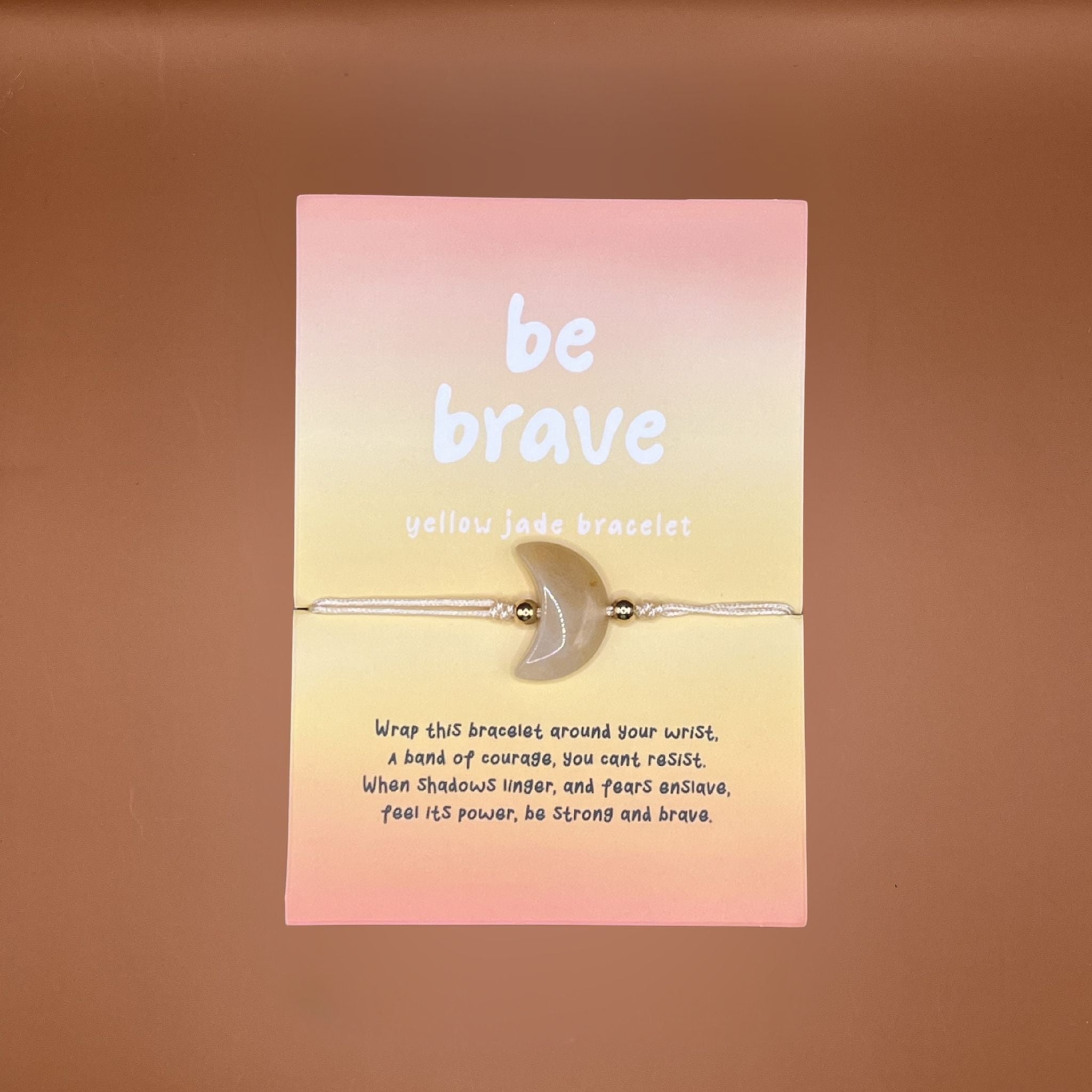 Yellow jade crescent moon bracelet on a yellow card with 'be brave' text