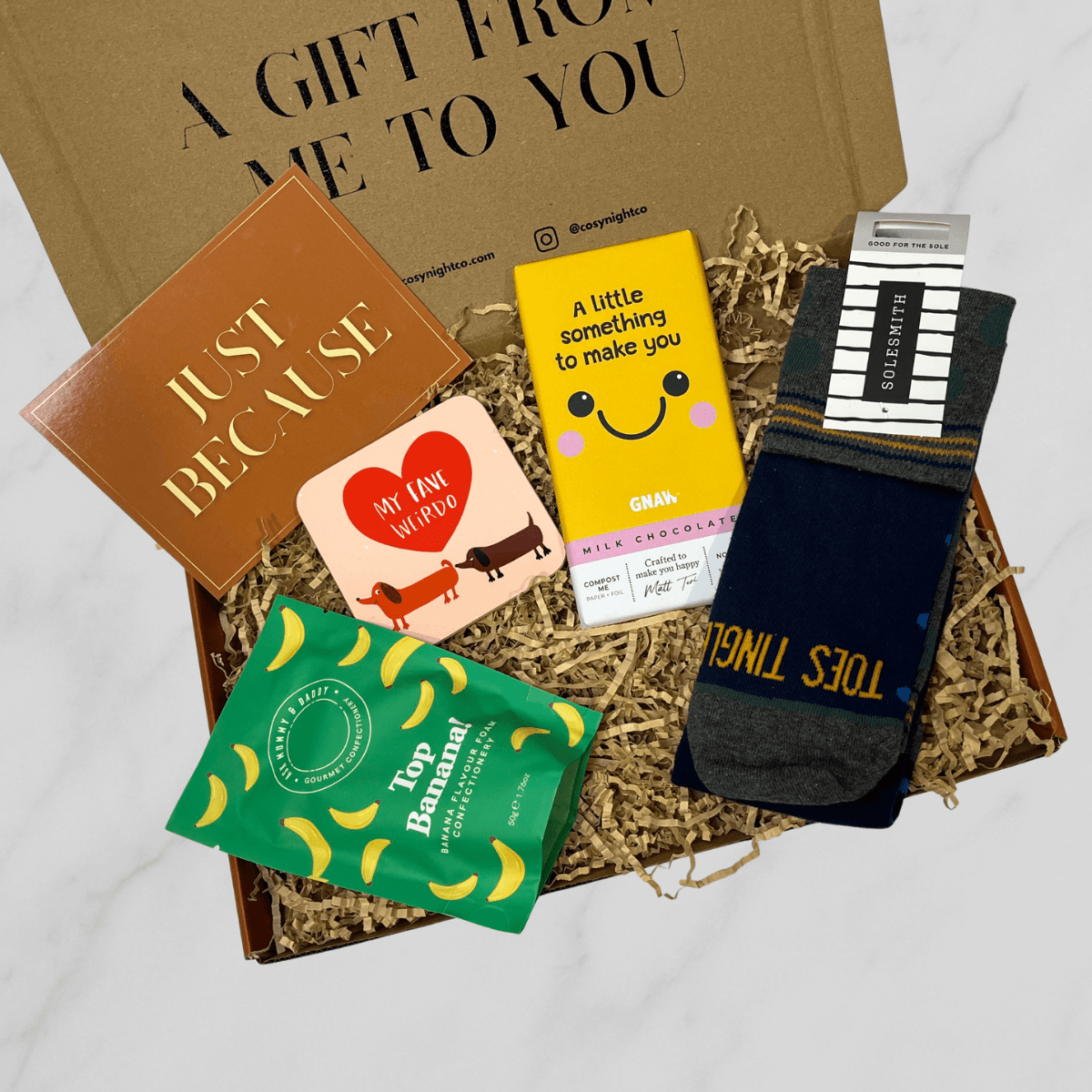 Just because letterbox gift box with socks, chocolate bar, banana sweets, and dachshund coaster