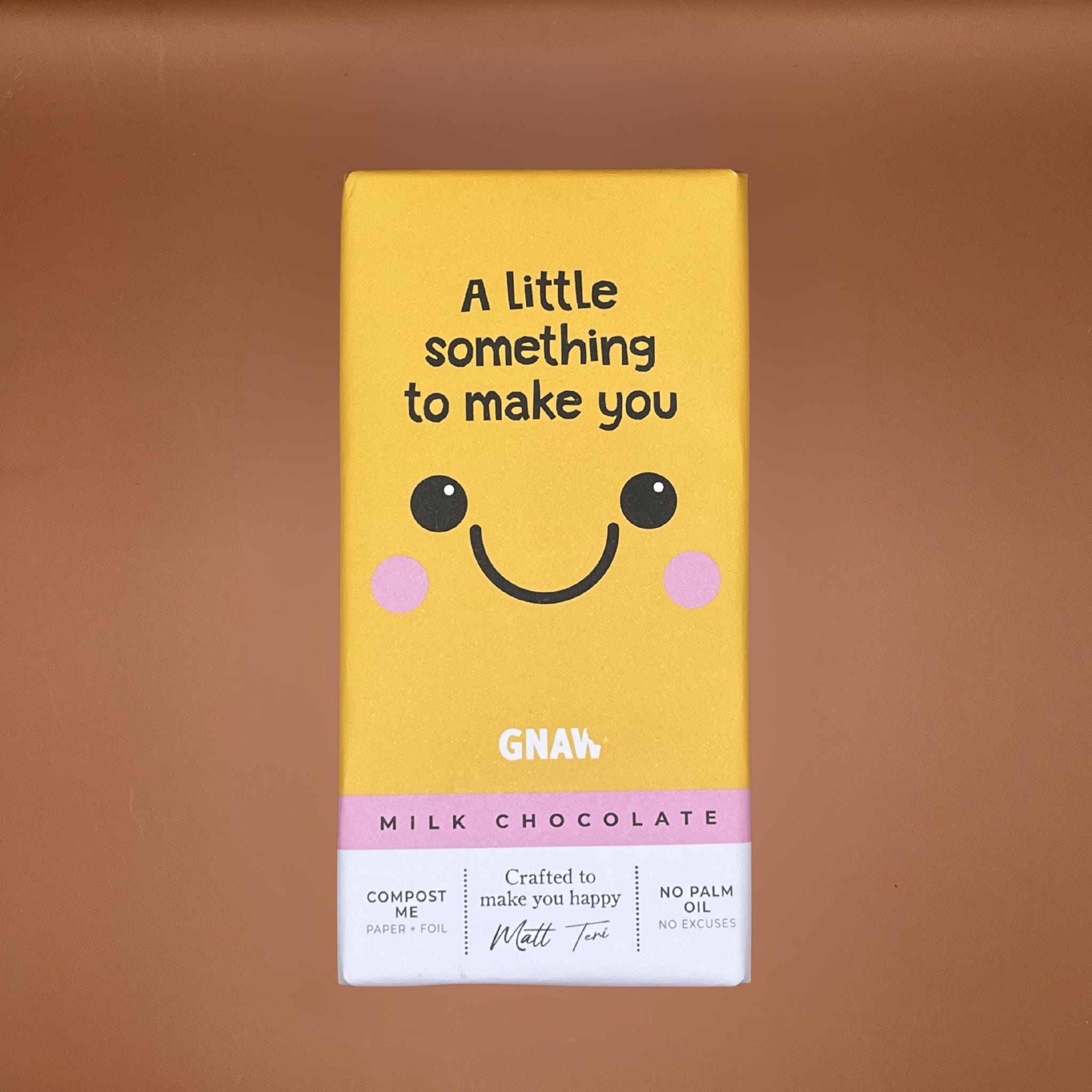 Yellow chocolate bar packaging with a smiley face on a brown background