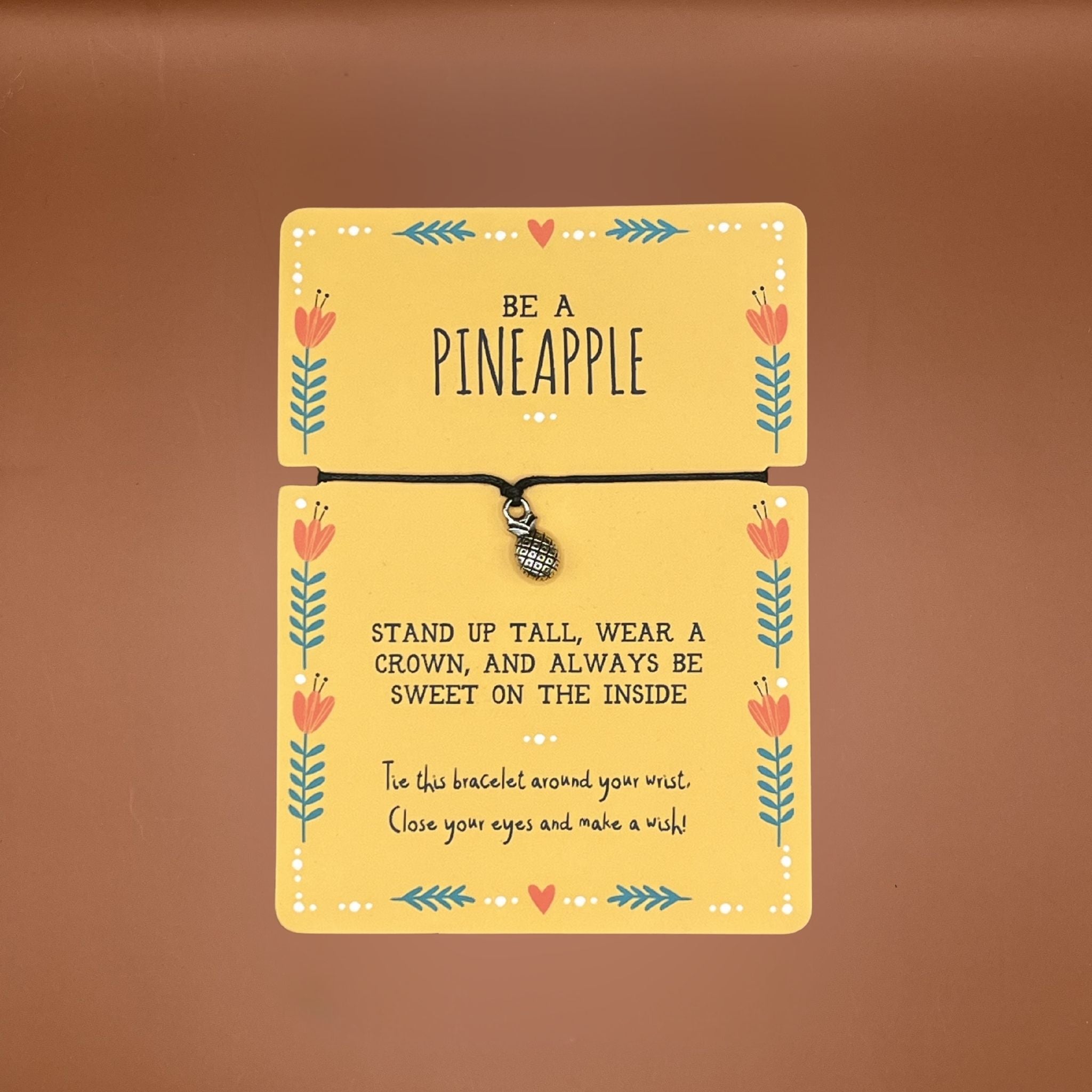 Bracelet with pineapple charm on a decorative card with text and floral patterns