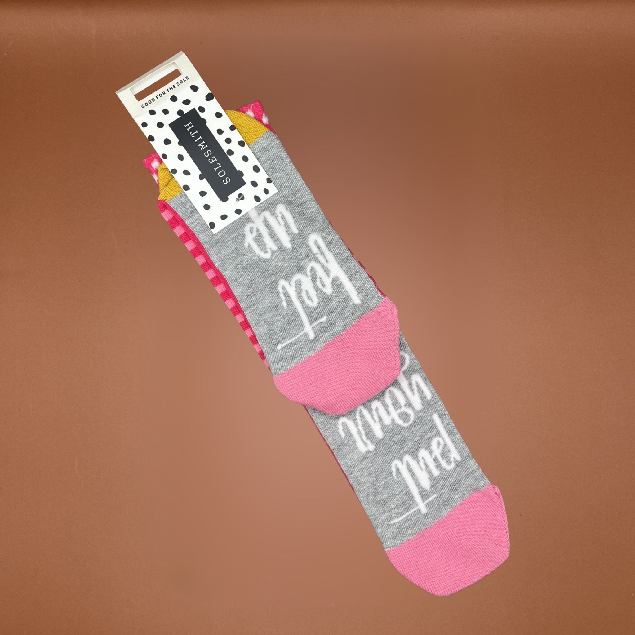 Gray and pink sock with text on a brown background