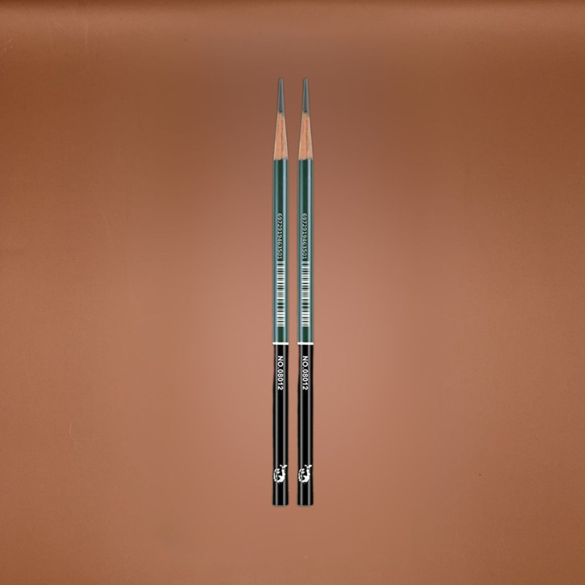 Two sketching pencils side by side on a solid brown background. The pencils have dark green barrels with white text, black lower sections, and exposed wood tips at the top.