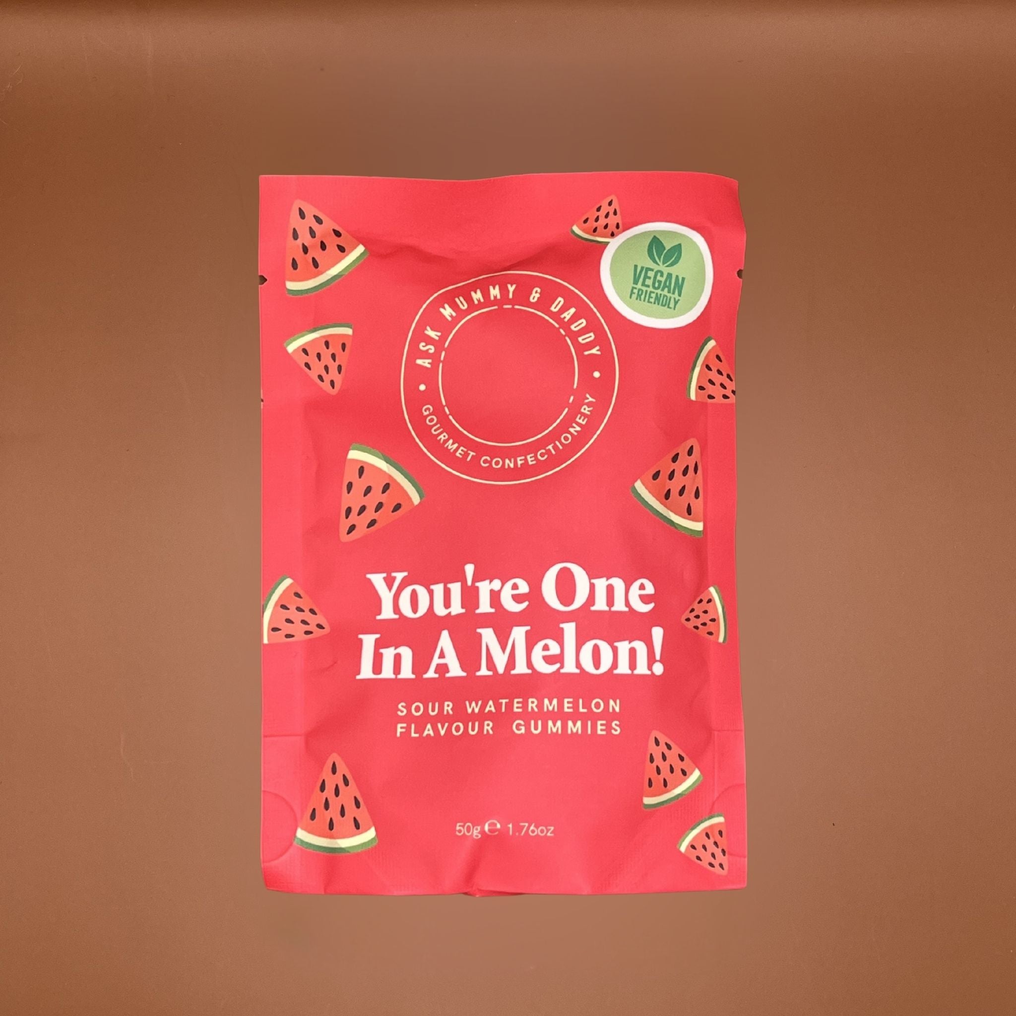 Red package of Sour Watermelon Flavour Gummies with watermelon slice graphics on a brown background