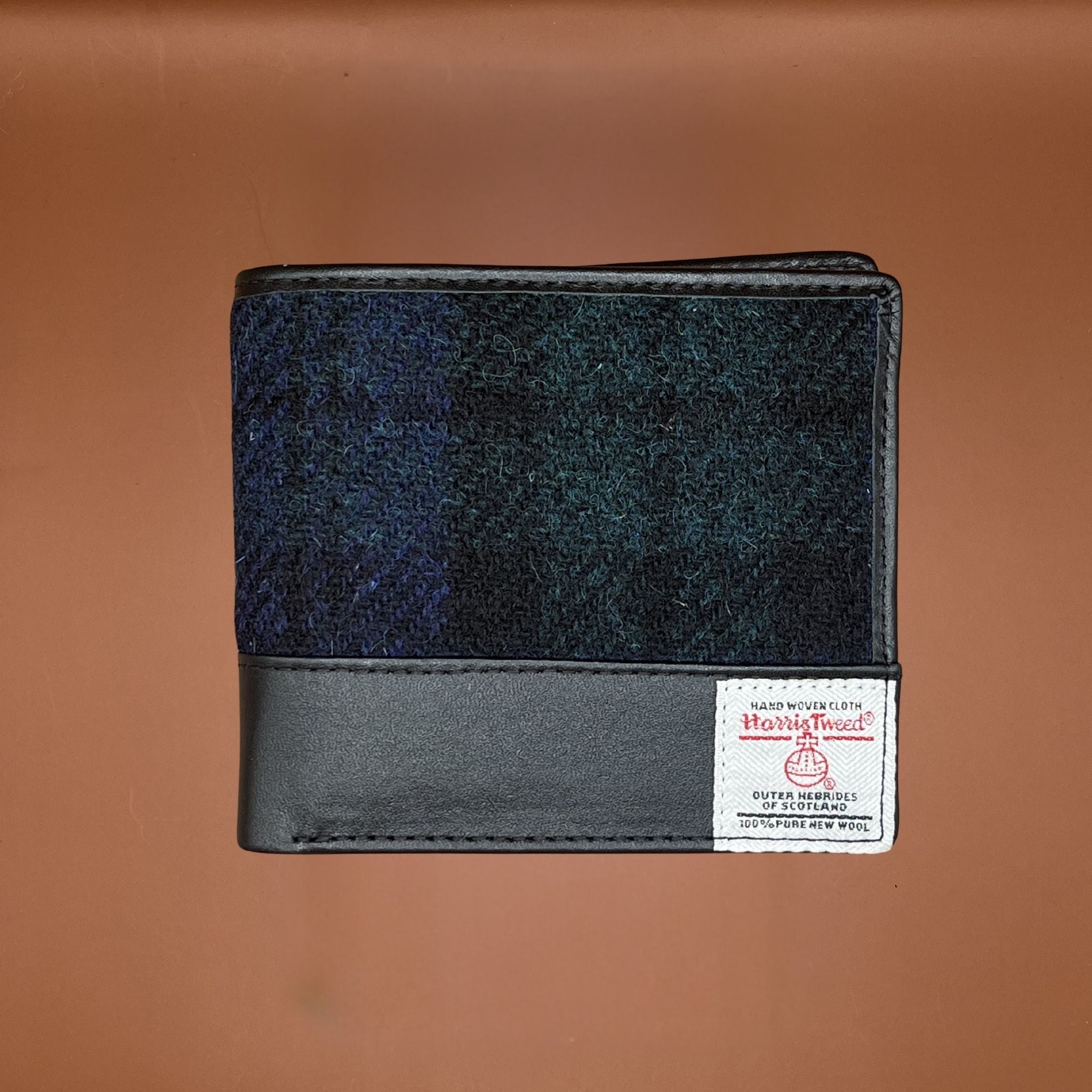 Wallet made from blue and green Harris Tweed fabric with black leather trim and a woven Harris Tweed label on the front.