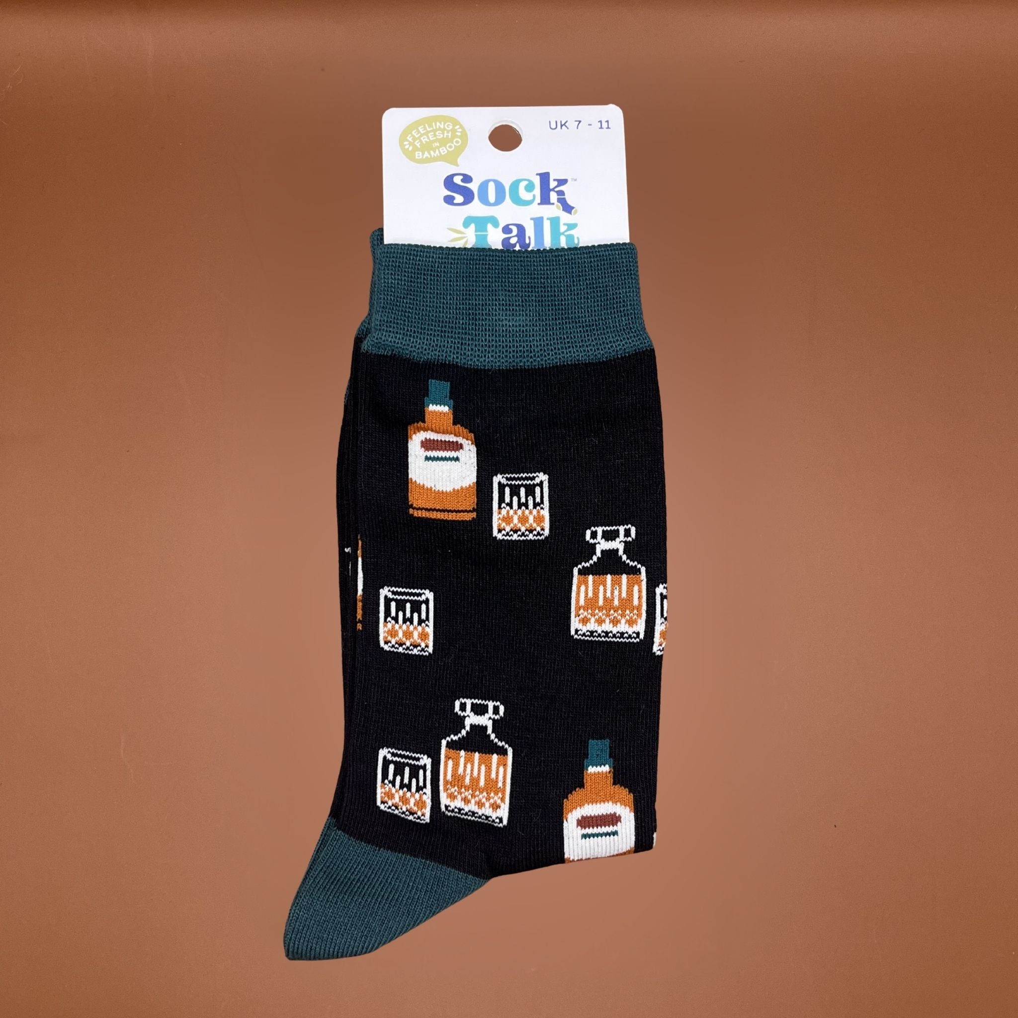 Pair of black bamboo socks with dark green cuffs and toes, featuring small orange whiskey bottles and glass patterns.