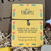 Yellow “Be a Pineapple” wish bracelet card with a small silver pineapple charm and motivational message.