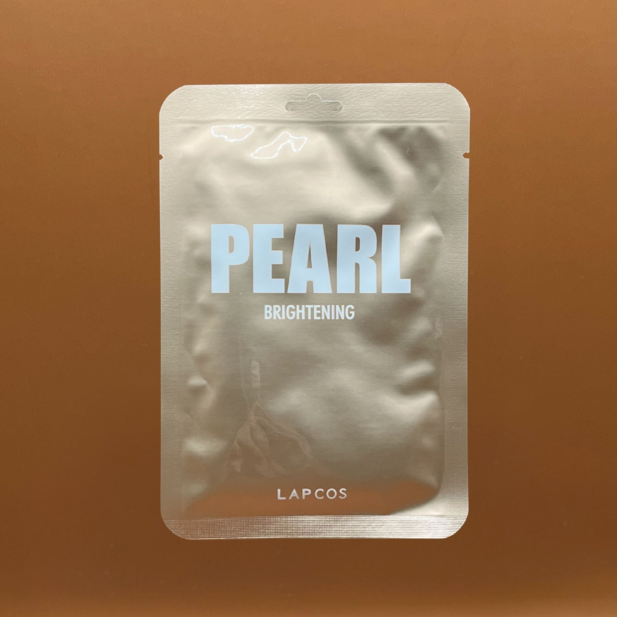 Pearl brightening product packaging with 'LAPCOS' branding on a brown background