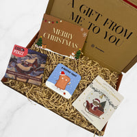 Festive Christmas gift box containing a Merry Christmas card, Coco Pzazz chocolate bar, festive toast coaster, and wish bracelet on shredded paper.