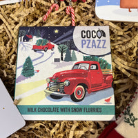 Festive Coco Pzazz Milk Chocolate with Snow Flurries bar featuring a vintage red truck and snowy winter landscape design.