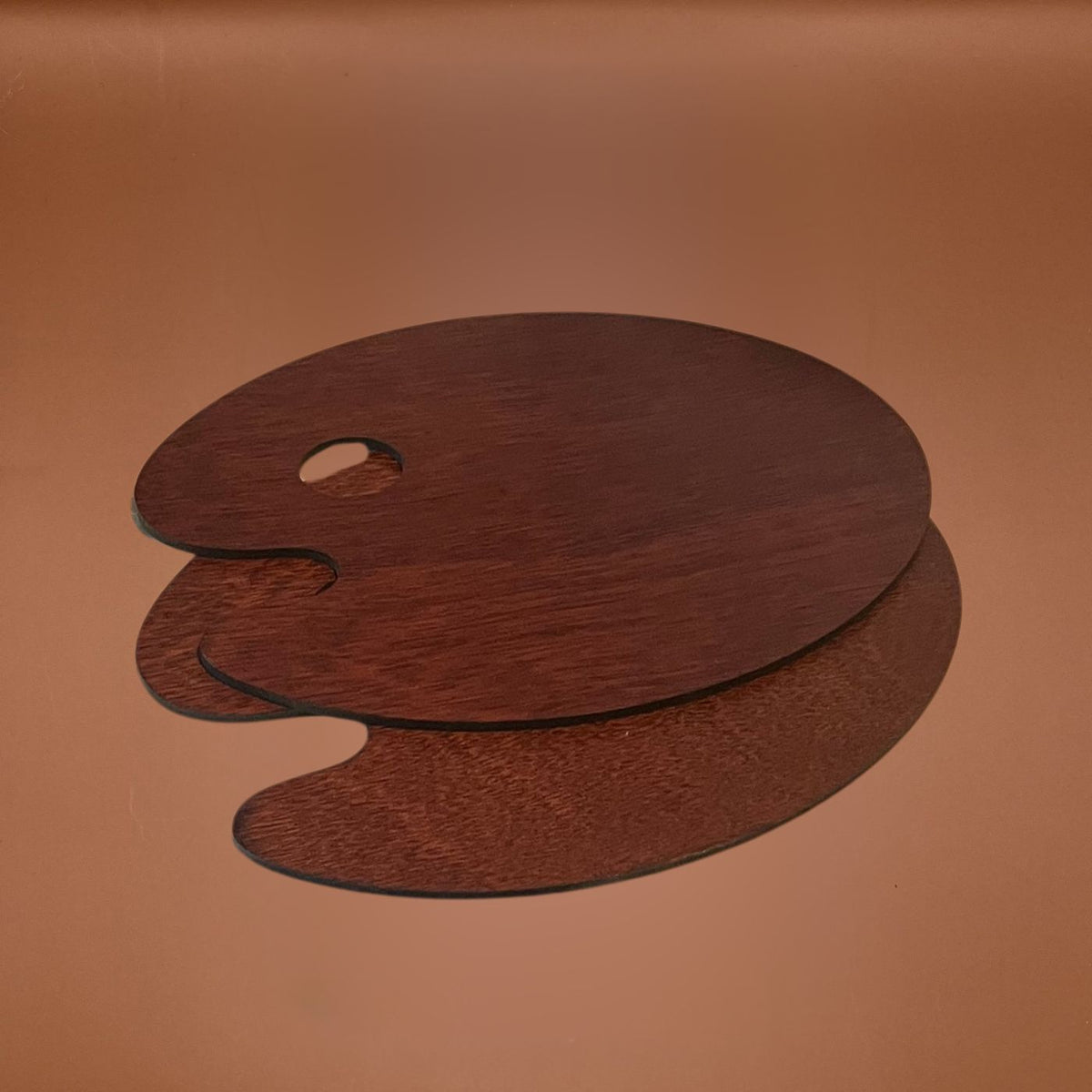2 dark brown wooden paint palette with a visible wood grain texture, displayed on a warm brown background.