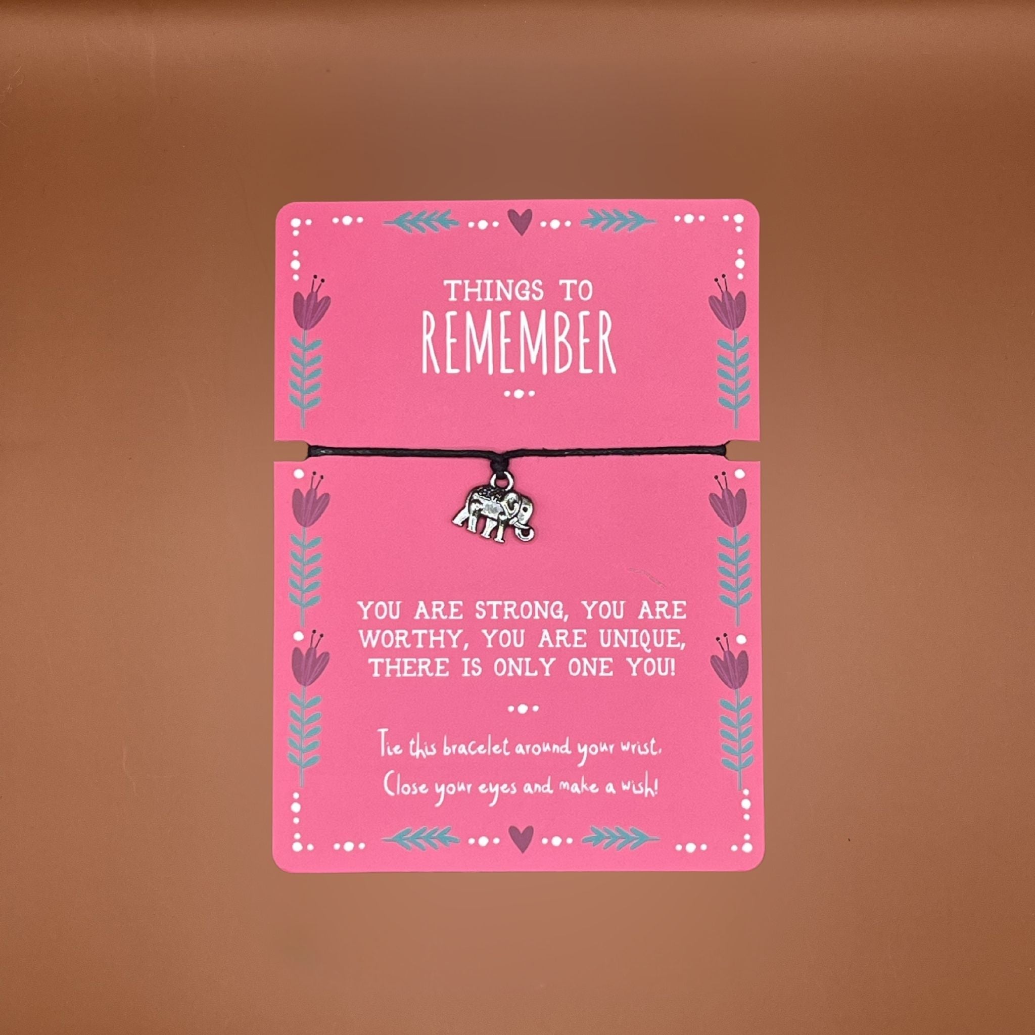Elephant pendant bracelet on a pink card with motivational message