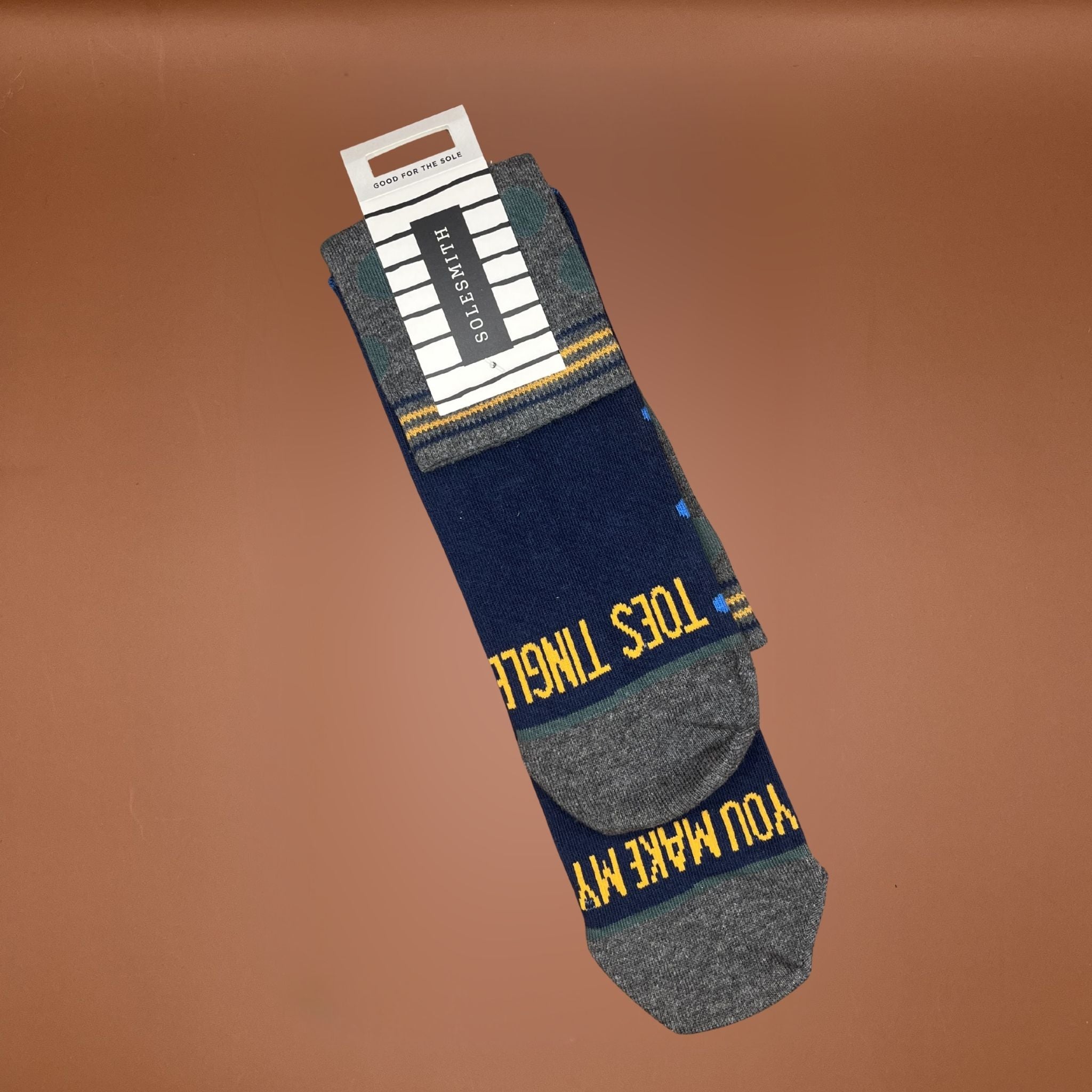 Pair of socks with text saying you make my toes tingle, on a brown background