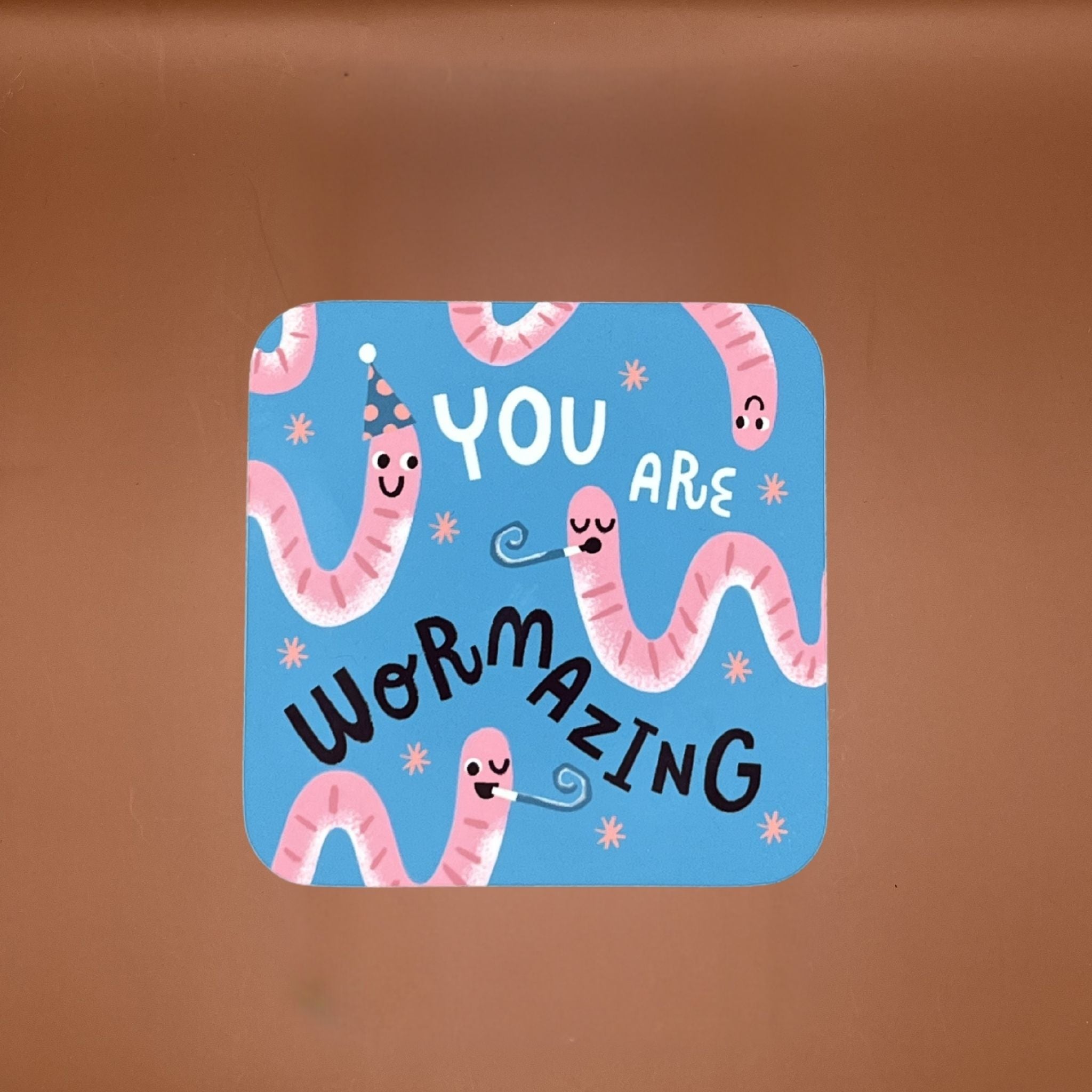 Cartoon worms coaster with text 'YOU ARE WORMAZING' on a blue background