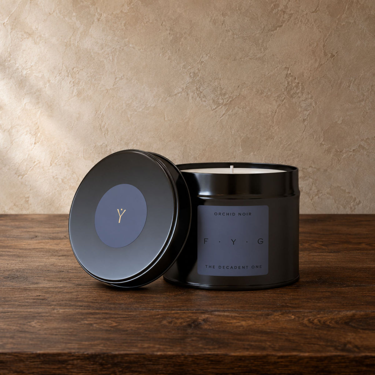 A matte black metal candle tin with its lid leaning against it on a dark wooden surface. The front label reads 'ORCHID NOIR' and 'F.
