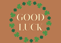 Good Luck text surrounded by green clover leaves on a brown background