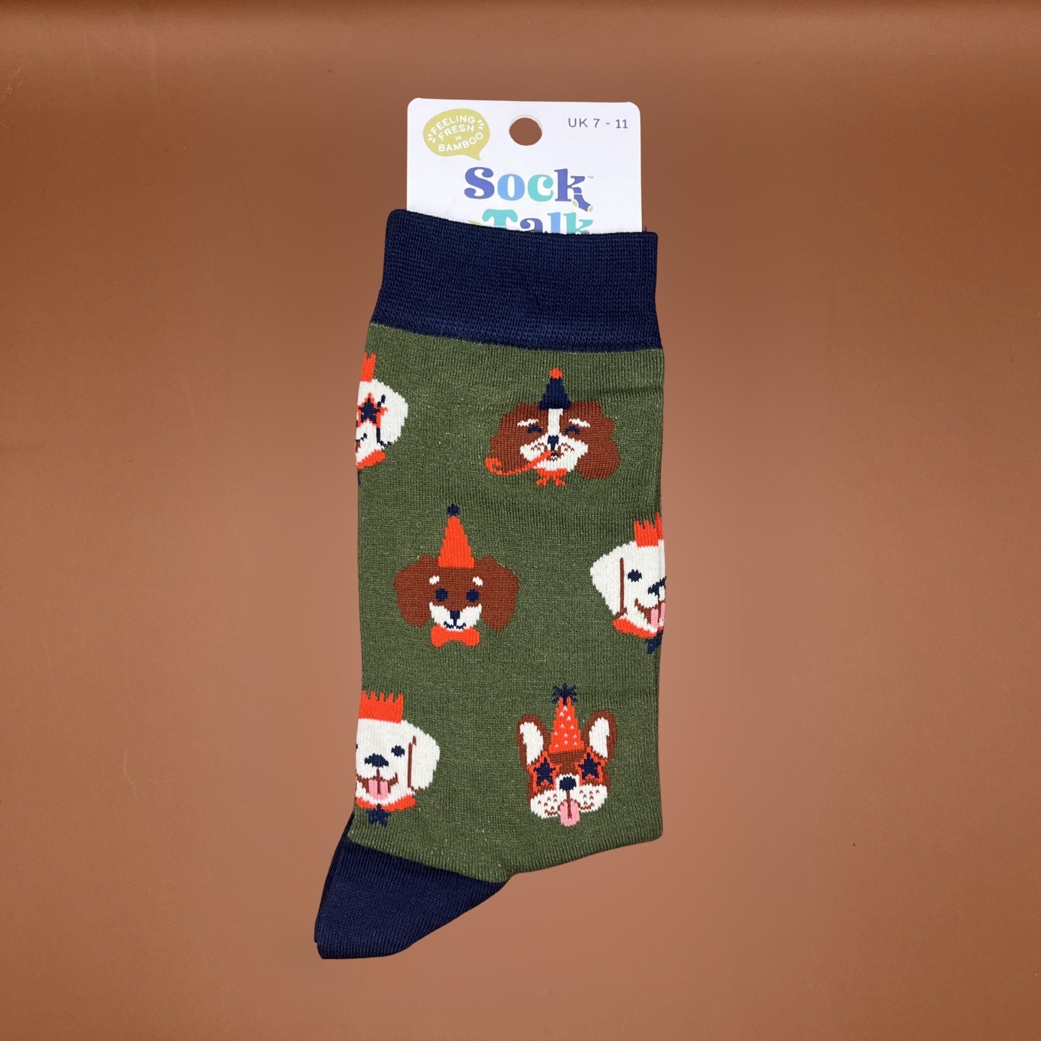 Pair of green socks with navy cuffs and heels, featuring colourful cartoon dog faces wearing party hats.