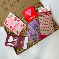 Letterbox gift box with heart socks, chocolate bar, gummies, tea bags and heart coaster.