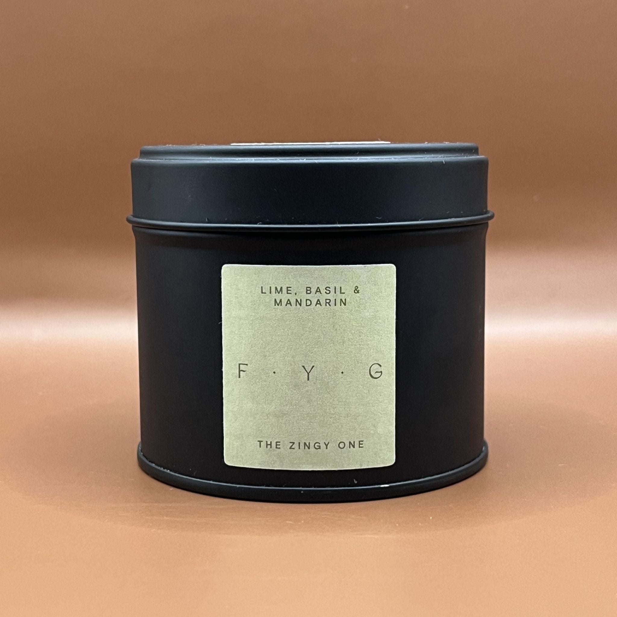 Black candle tin with a green label saying lime, basil and mandarin