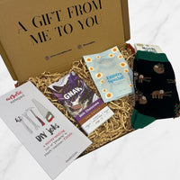 Letterbox gift box containing a DIY notepad, GNAW milk chocolate bar, Eggstra Special gummy sweets, and green sloth-patterned socks.