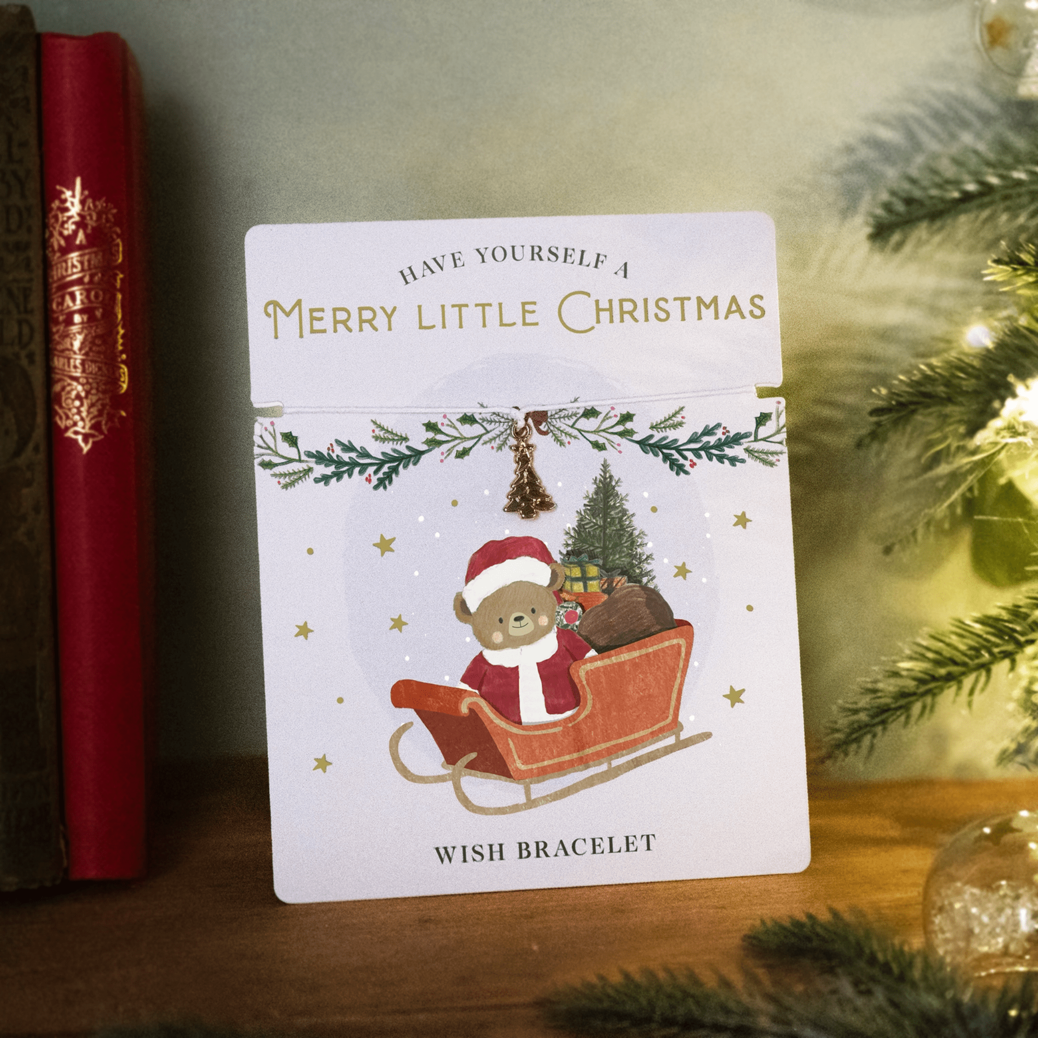 Christmas-themed card with a bear in a sleigh and Christmas text, placed on a wood surface.