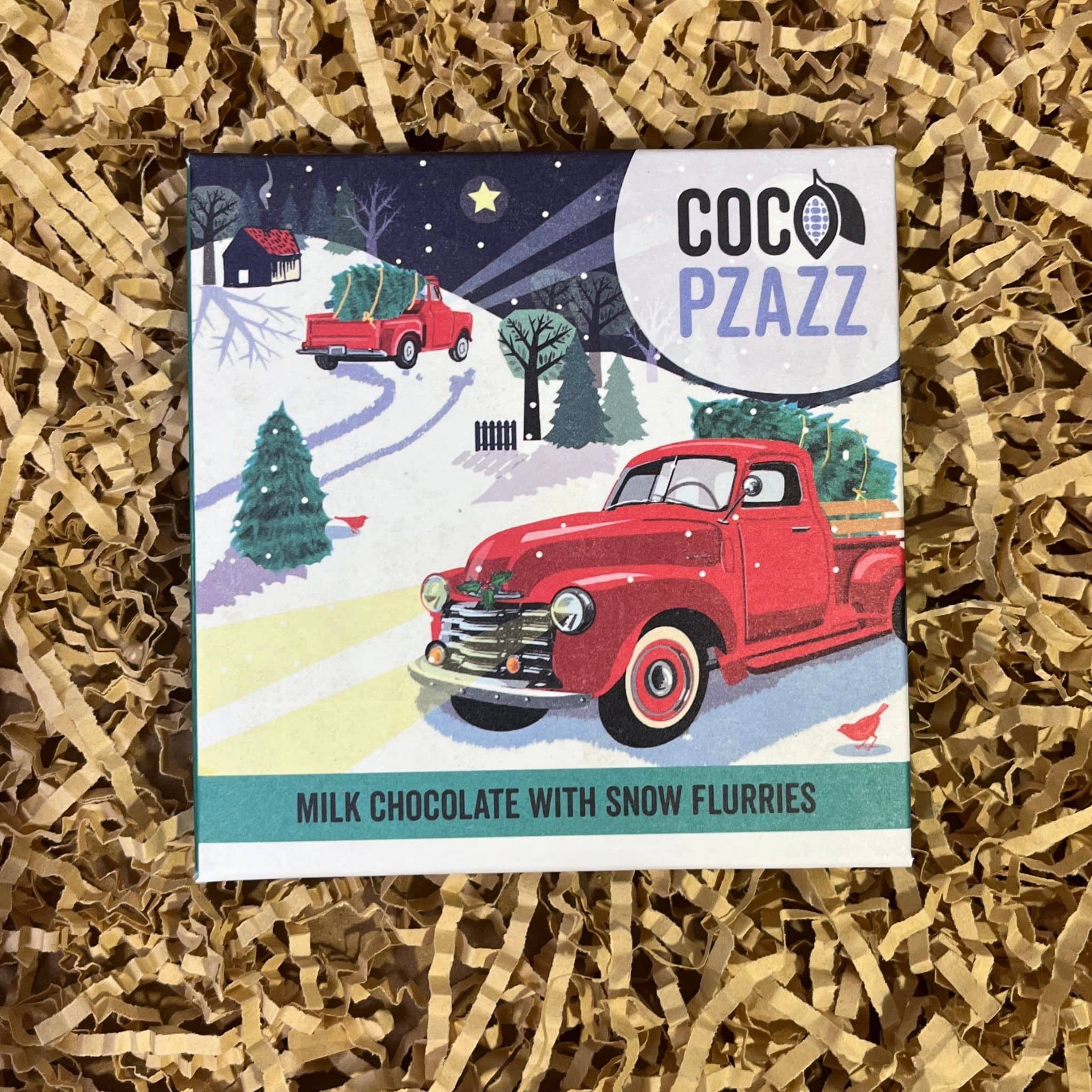 Coco Pzazz Milk Chocolate with Snow Flurries bar featuring a red vintage truck carrying a Christmas tree in a snowy winter scene.