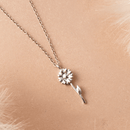Silver sunflower necklace on a beige background.