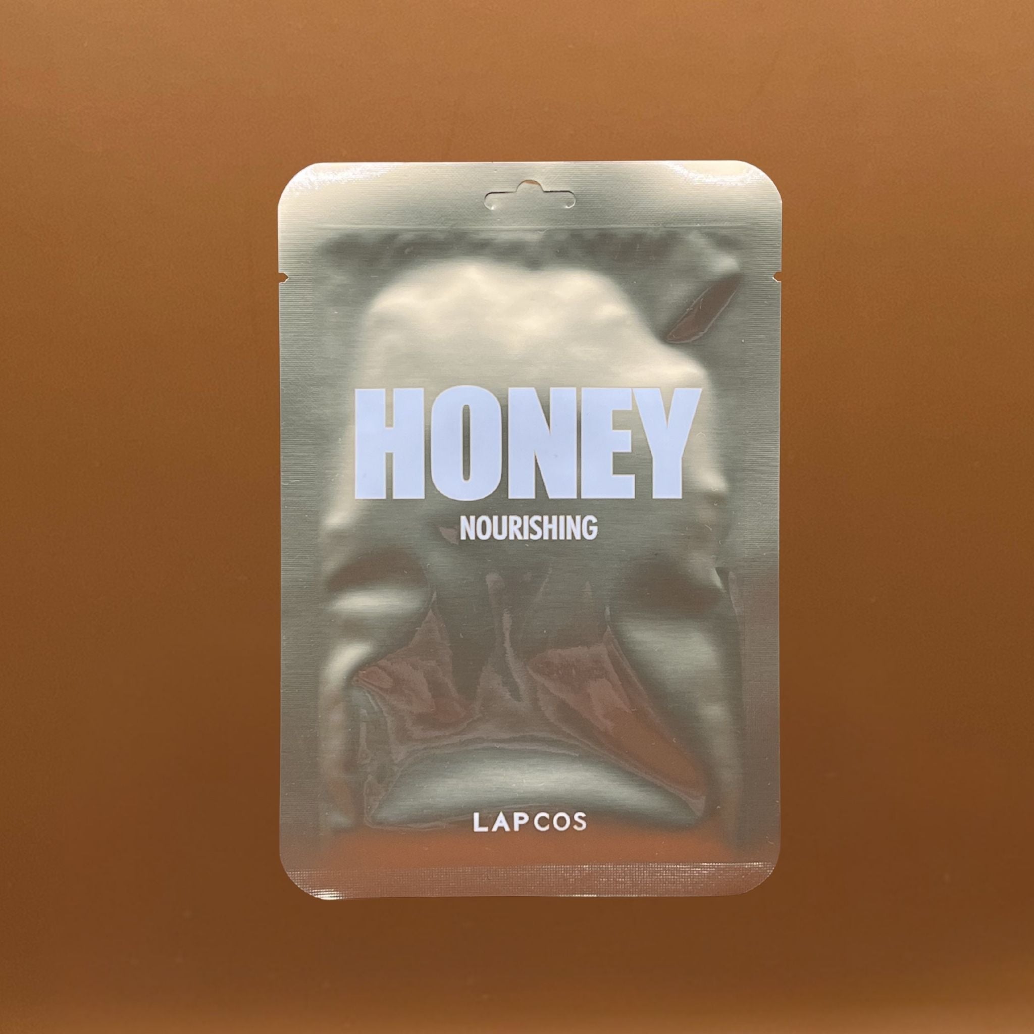 LAPCOS honey nourishing product packaging on a brown background