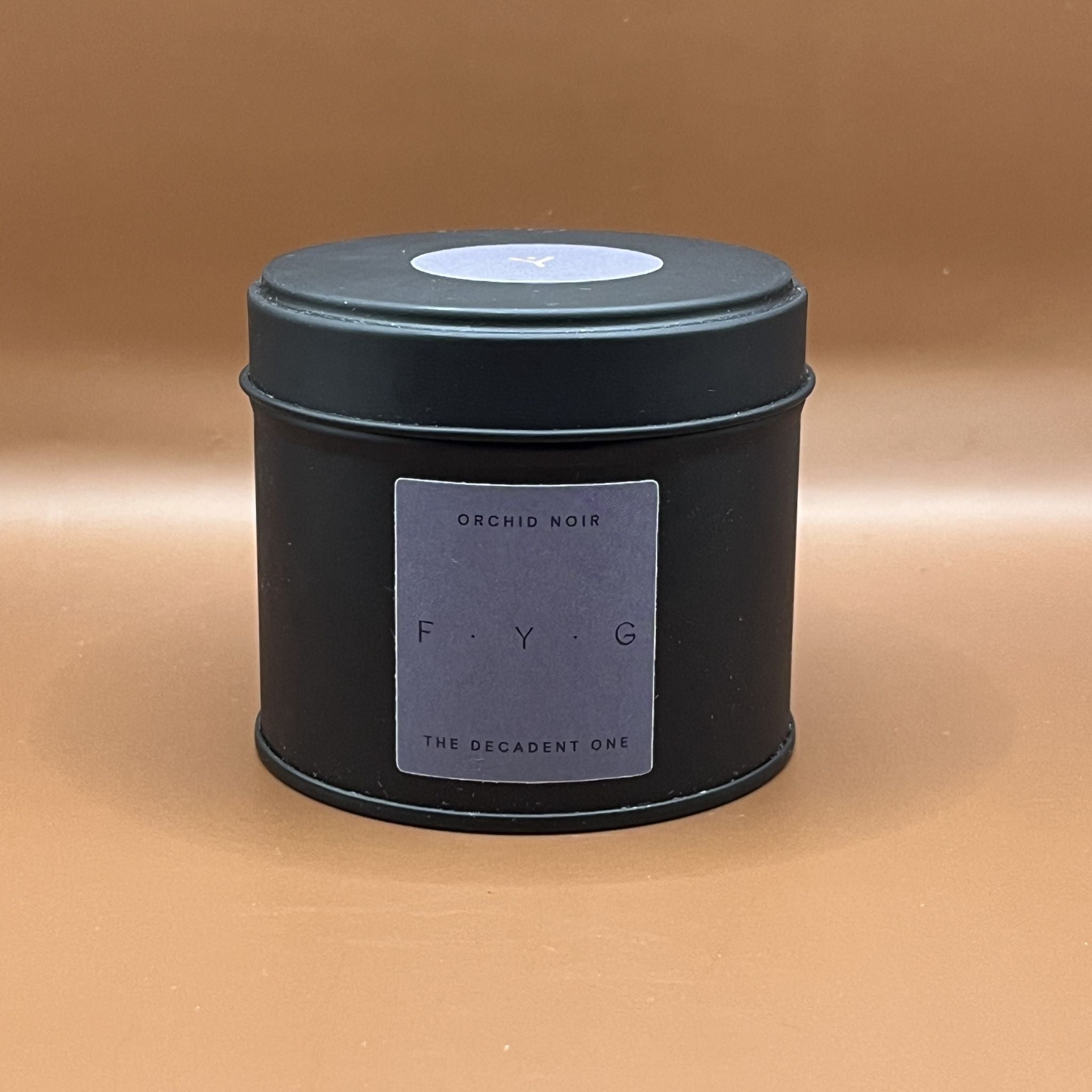 Black candle tin with a purple label on saying orchid noir
