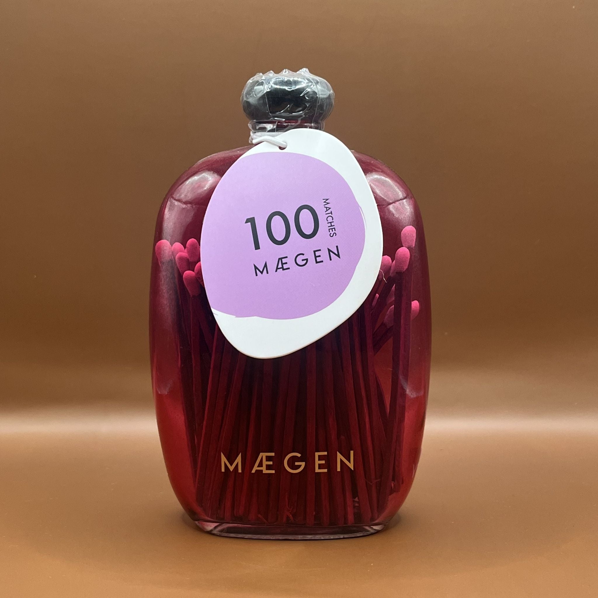 Pink glass bottle with pink matches inside and maegen branding on the bottom