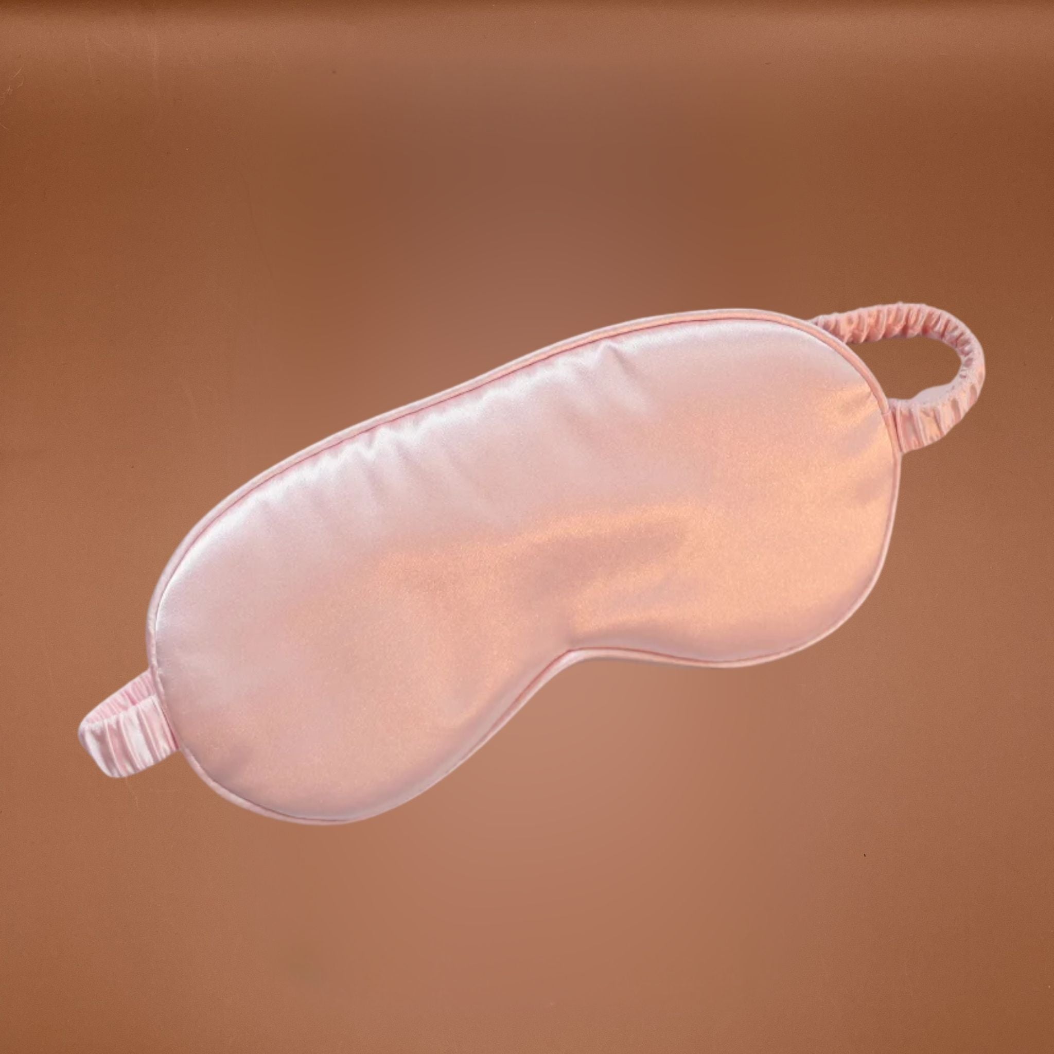 Pink satin eye mask on a brown background