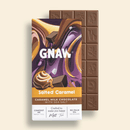 GNAW salted caramel chocolate bar with packaging on a beige background