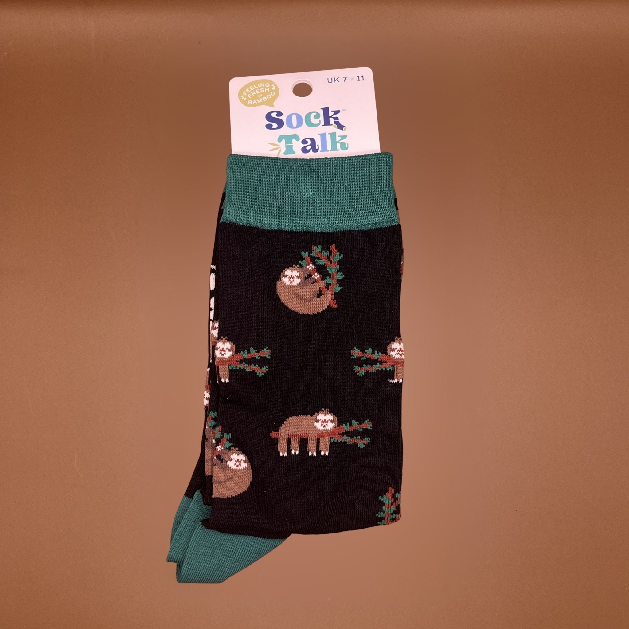 Black socks with green heels and cuffs, featuring a sloth hanging off a branch pattern.