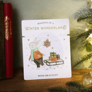 Wish bracelet with a snowflake charm displayed on a festive card showing a rabbit pulling a sled with presents.