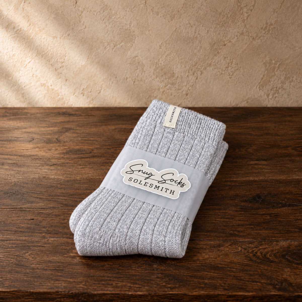 soft grey wool socks placed on a dark oak surface against a beige textured wall.