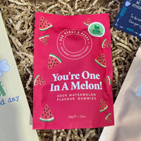 Bright pink packet of “You’re One In A Melon!” sour watermelon vegan gummies by Ask Mummy & Daddy, placed on shredded paper