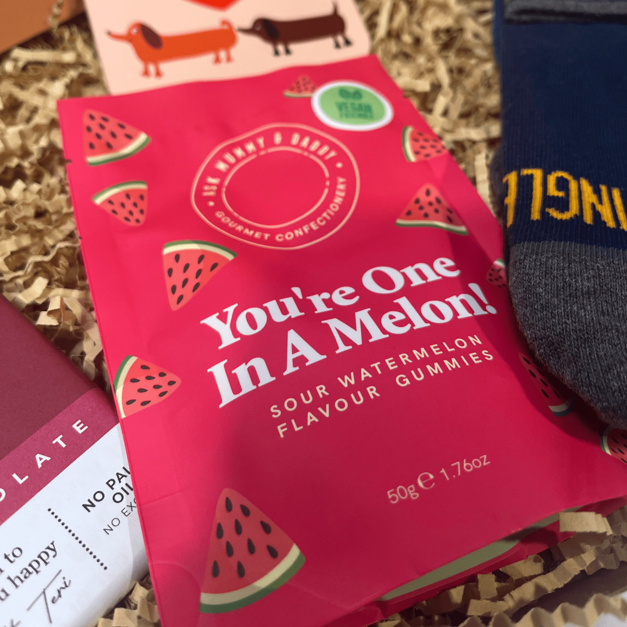 Close-up of You’re One In A Melon sour watermelon gummies inside letterbox gift box.