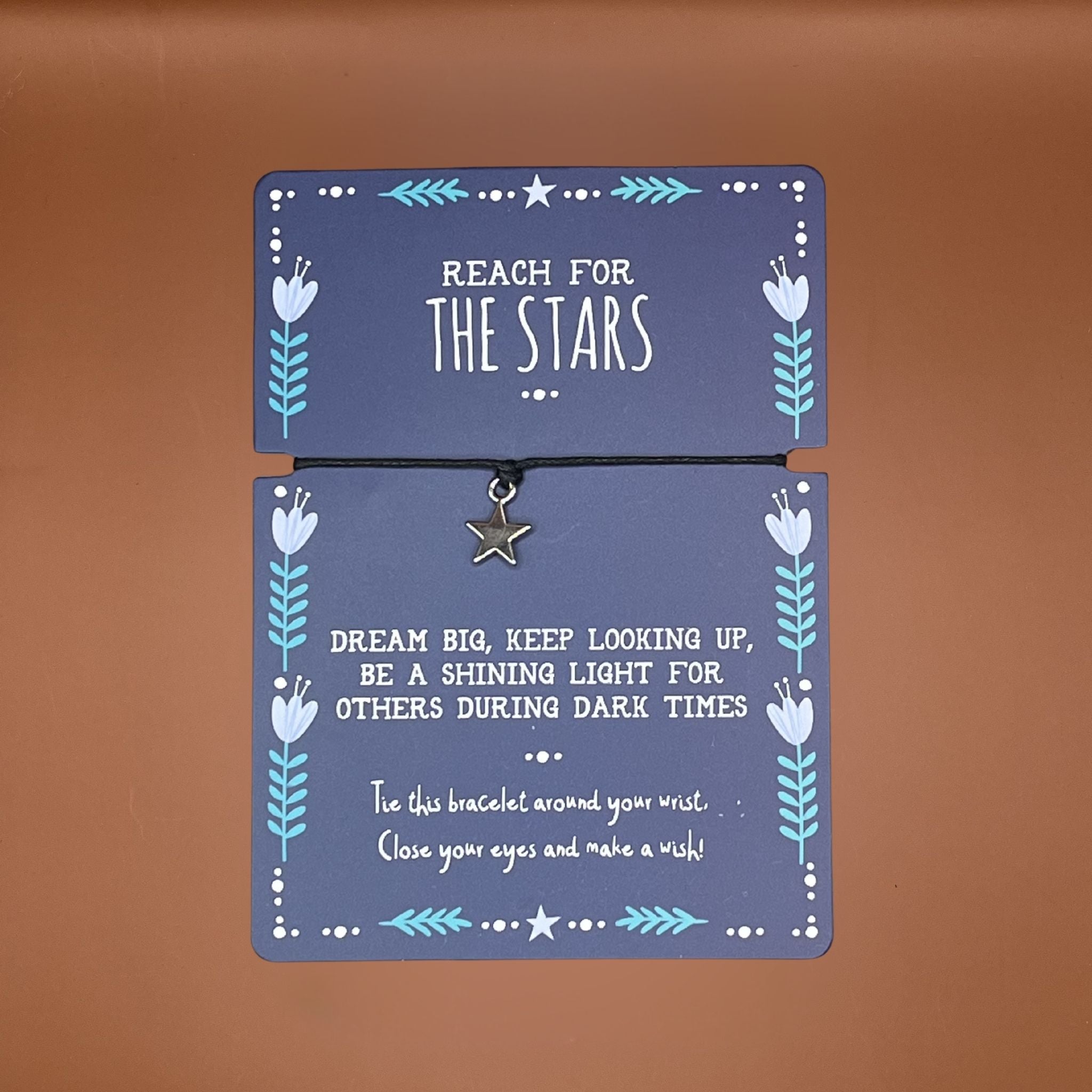 Bracelet with star charm on a blue card with motivational text saying reach for the stars.