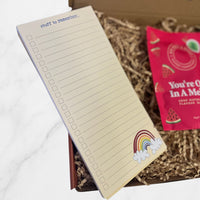 Open positivity-themed notepad with “Stuff to remember” heading and checklist design, placed beside watermelon gummies in a gift box