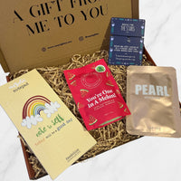 Gift box filled with a rainbow notepad, watermelon gummies, pearl brightening face mask, and a “Reach for the Stars” bracelet