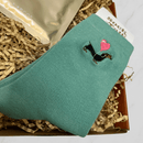 Close-up of green dachshund socks with heart design inside letterbox gift box.