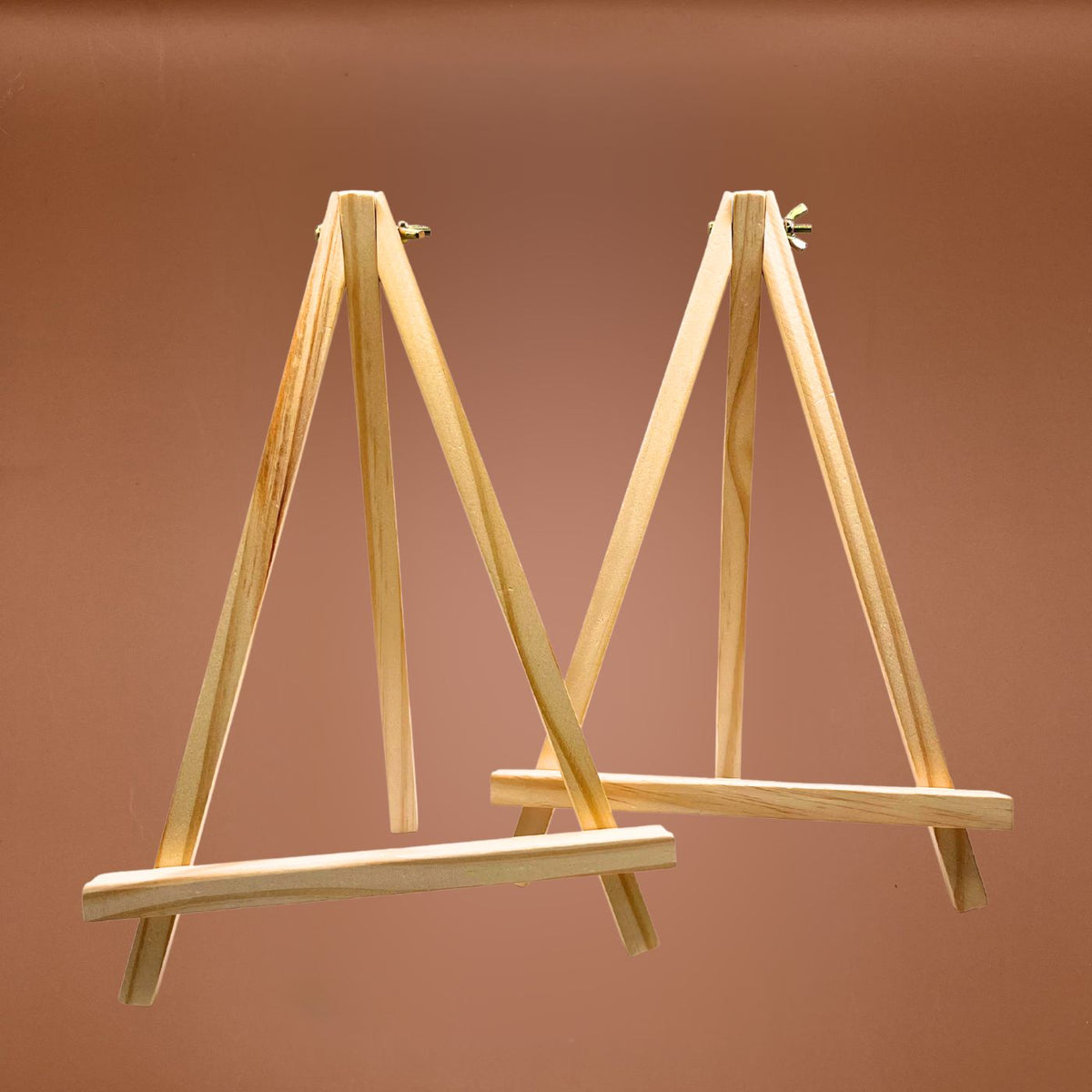 Two wooden easels with adjustable legs, shown against a solid warm brown background.